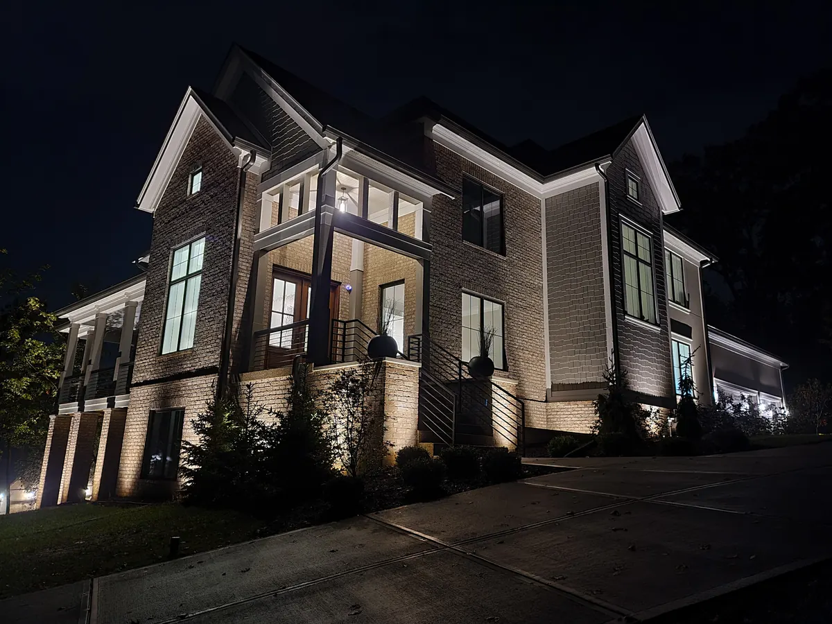 Multi-level Indianapolis home with layered facade uplighting and warm accent lights across the architectural details